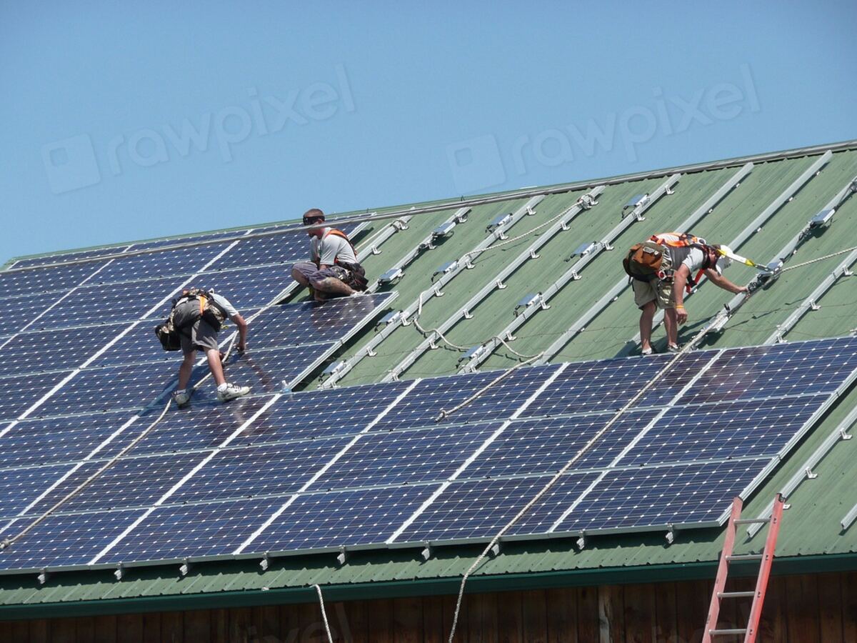 Technicians maintaining rooftop solar panels near the coast